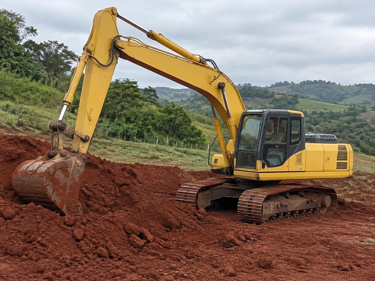Escavadeira trabalhando em terreno de solo vermelho